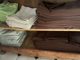 many folded towels on a wooden shelf in a bathroom