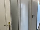 un réfrigérateur blanc dans un coin de la pièce, près d'une porte