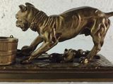 bronze statue of a dog with a bucket on a table