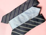 three ties are stacked on top of each other on a pink background