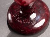 a red vase sitting on a table with writing on it