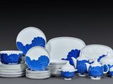 Des assiettes et des tasses bleues et blanches sont disposées sur une surface grise
