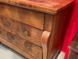 a wooden chest of drawers in a room with a red wall