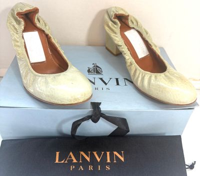 une paire de chaussures beiges ornées de nœuds, posée sur une boîte