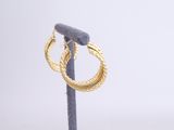 a close up of a pair of gold hoop earrings on a stand