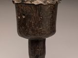 une image représentant une tasse en bois munie d'une anse, posée sur un socle