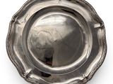 an antique silver plate on a white background with a reflection of a person