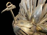 a silver bird made out of spoons on a black background