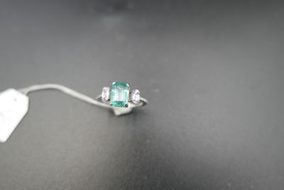 une bague en émeraude et diamants posée sur une table, avec une étiquette indiquant son prix