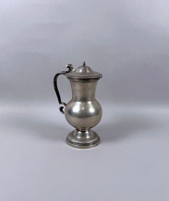 une cafetière ancienne en métal argenté, munie d'une anse, sur fond blanc