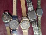 several watches are sitting on a table with a red cloth