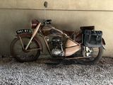 a old motorcycle parked next to a wall with a bag on it