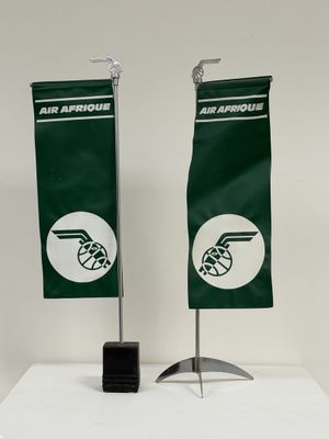 deux drapeaux verts et blancs fixés sur un support posé sur une surface blanche