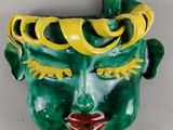 un masque vert et jaune sur un mur blanc