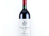 the bottle of red wine is sitting on a white surface