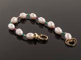 a close up of a white pearl bracelet with a gold clasp
