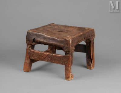 an old wooden stool sitting on top of a gray surface
