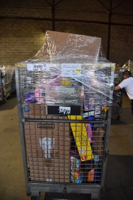 a cart full of items in a warehouse with a man walking by