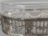a silver plate with a glass bowl on top of it
