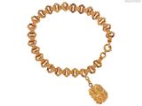 bracelet plaqué or orné d'une breloque en forme de pièce d'or sur fond blanc