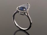 a blue sapphire and diamond ring on a reflective surface