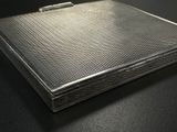 an image of a silver cigarette case sitting on a black surface