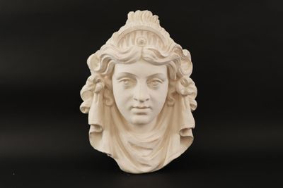 a close up of a sculpture of a woman ' s face on a black surface