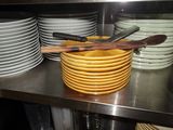 many plates and spoons stacked on a shelf in a kitchen