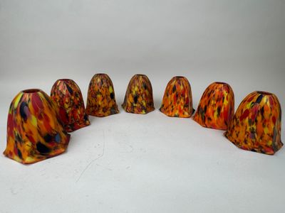 six vases orange et jaunes alignés sur une surface blanche