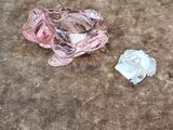 un objet en verre rose posé par terre à côté d'un morceau de verre cassé