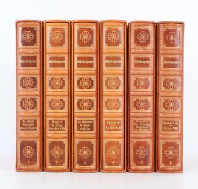six vieux livres sont alignés sur une surface blanche