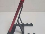 a red cell phone on a black stand on a white table