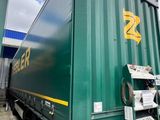 a large green container truck parked in a parking lot