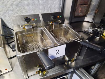 two deep fryers sitting on a table in a kitchen