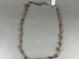 a close up of a necklace on a table with a tag attached to it