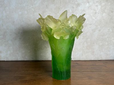 un vase vert contenant des fleurs, posé sur une table