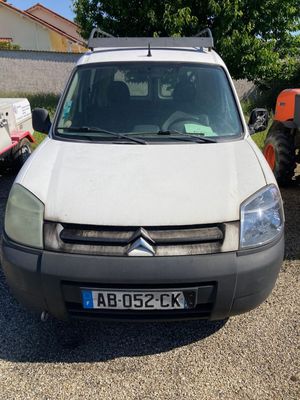 La camionnette blanche est garée à côté d'un tracteur dans l'allée.