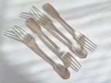 five forks and a spoon on a white table cloth