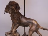 bronze statue of a dog on a rock with a bird in it ' s mouth