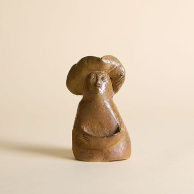 une figurine représentant une femme portant un chapeau sur la tête