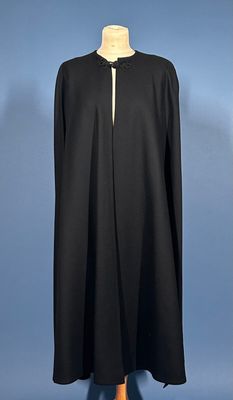 a black cape on a mannequin stand against a blue background