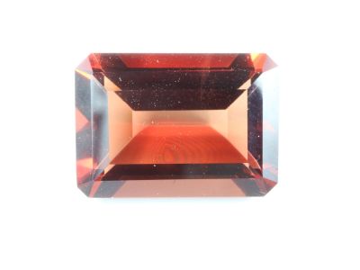 une tourmaline orange taillée sur fond blanc
