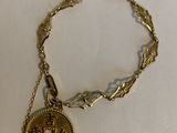 a close up of a gold bracelet with a coin on it