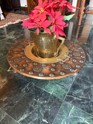 un vase en or orné de fleurs rouges posé sur une table en marbre
