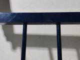 a black metal chair with a blue seat and a white wall in the background