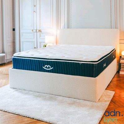 une photo d'un matelas dans une chambre à coucher avec un tapis blanc