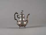 an antique silver teapot with a bird on the top of it