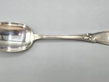 an antique silver spoon on a white surface with a silver handle