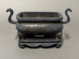 a small metal bowl with two handles on a stand