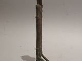 statue of a bird perched on a wooden pole on a white background